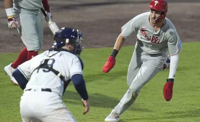 Philadelphia Phillies' Trea Turner, right, prepares to score in front of Tampa Bay Rays catcher Danny Jansen on a two-run double by Bryce Harper during the fourth inning of a baseball game Wednesday, May 7, 2025, in Tampa, Fla. (AP Photo/Chris O'Meara)