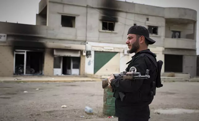 A fighter of Syria's security forces is deployed at a highway where they found the bodies of Syrian Druze fighters who were in a convoy heading from the southern Sweida province towards the capital, at al-Sor al-Kobra village near the Sweida town, southern Syria, Thursday, May 1, 2025. (AP Photo/Omar Albam)