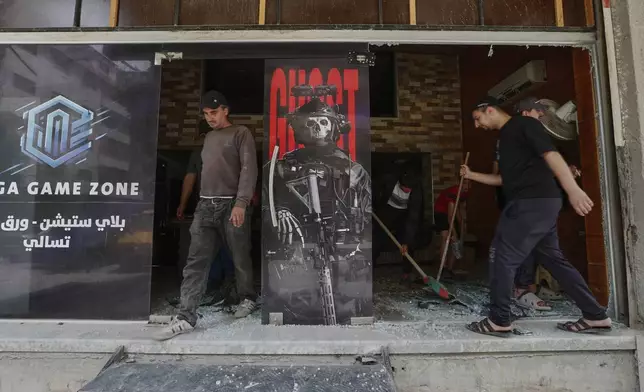 People clean a shop that was damaged after clashes erupted between members of the minority Druze sect and pro-government fighters, i in the town of Sahnaya, south of Damascus, Syria, Thursday, May 1, 2025. (AP Photo/Omar Sanadiki)