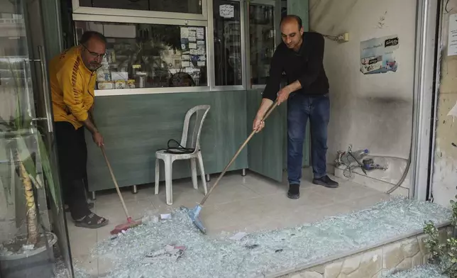 People remove shattered glass from a shop that was damaged after clashes erupted between members of the minority Druze sect and pro-government fighters, in the town of Sahnaya, south of Damascus, Syria, Thursday, May 1, 2025. (AP Photo/Ghaith Alsayed)