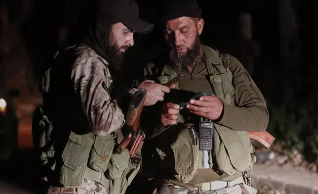 Syria's security forces check their mobile phones at a checkpoint, after reaching a deal with Druze gunmen to deploy around Jaramana, a Damascus suburb that saw fighting earlier this week, in Damascus, Syria, early Friday, May 2, 2025. (AP Photo/Omar Sanadiki)
