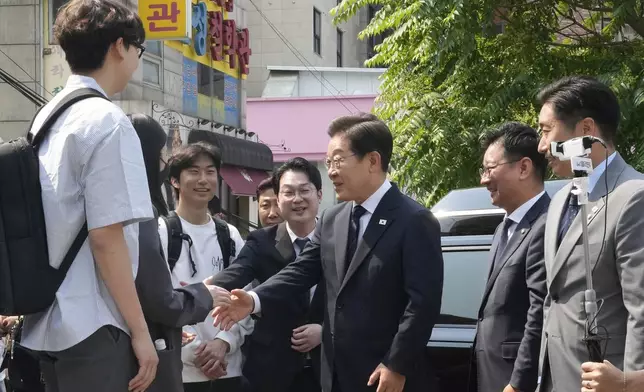 South Korean Democratic Party's presidential candidate Lee Jae-myung, center, is greeted by young people upon his arrival at a polling station in Seoul, South Korea, Thursday, May 29, 2025. (AP Photo/Ahn Young-joon)