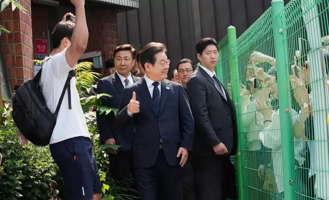 South Korean Democratic Party's presidential candidate Lee Jae-myung, center, reacts as he leaves after casting his early vote for the June 3 presidential election near a polling station in Seoul, South Korea, Thursday, May 29, 2025. (AP Photo/Ahn Young-joon)