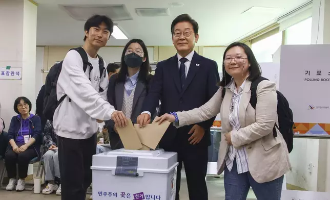South Korean Democratic Party's presidential candidate Lee Jae-myung, second from right, and young people pose as they cast their early votes for the June 3 presidential election at a polling station in Seoul, South Korea, Thursday, May 29, 2025. (Yonhap via AP)