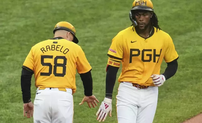 Pittsburgh Pirates' Oneil Cruz, right, celebrates with third base coach Mike Rabelo (58) as he rounds third after hitting a solo home run off Milwaukee Brewers pitcher Freddy Peralta during the third inning of a baseball game in Pittsburgh, Friday, May 23, 2025. (AP Photo/Gene J. Puskar)