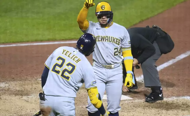 Milwaukee Brewers' William Contreras (24) celebrates with Christian Yelich as he returns to the dugout after hitting a solo home run off Pittsburgh Pirates pitcher David Bednar during the ninth inning of a baseball game in Pittsburgh, Friday, May 23, 2025. (AP Photo/Gene J. Puskar)