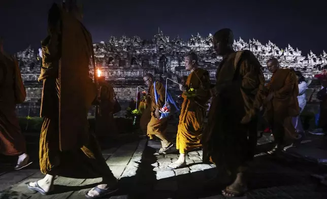 Buddhist monks walk around the 9th-century Borobudur Temple during the commemoration of Vesak, which marks the day of Buddha's birth, death and enlightenment, in Magelang, Central Java, Indonesia, early Tuesday, May 13, 2025. (AP Photo/Slamet Riyadi)