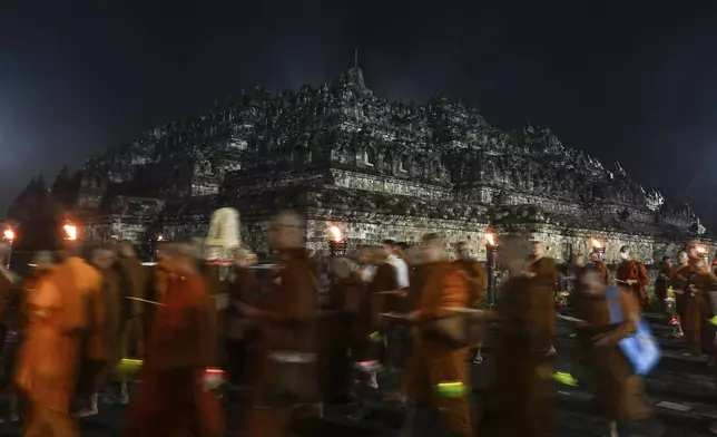 Buddhist monks walk around the 9th-century Borobudur Temple during the commemoration of Vesak, which marks the day of Buddha's birth, death and enlightenment, in Magelang, Central Java, Indonesia, early Tuesday, May 13, 2025. (AP Photo/Slamet Riyadi)