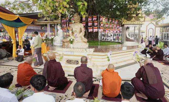 Buddhist monks and devotees pray at foot of a banyan tree during a religious ceremony to mark the Full Moon day of "Kasone," known as Buddha's Birthday, at Botataung pagoda Sunday, May 11, 2025, in Yangon, Myanmar. (AP Photo/Thein Zaw)