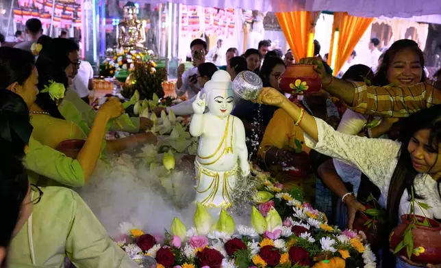 Buddhist devotees pour water to childhood statue of Buddha during a religious ceremony to mark the Full Moon day of "Kasone," known as Buddha's Birthday, at Botataung pagoda Sunday, May 11, 2025, in Yangon, Myanmar. (AP Photo/Thein Zaw)