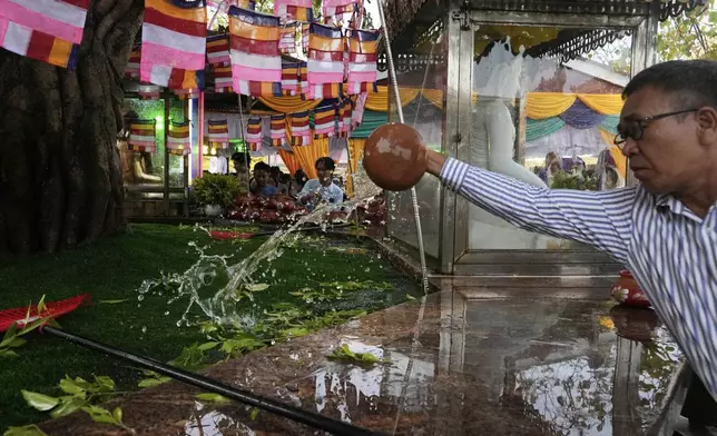 A Buddhist devotee pours water to foot of a banyan tree during a religious ceremony to mark the Full Moon day of "Kasone," known as Buddha's Birthday, at Botataung pagoda Sunday, May 11, 2025, in Yangon, Myanmar. (AP Photo/Thein Zaw)