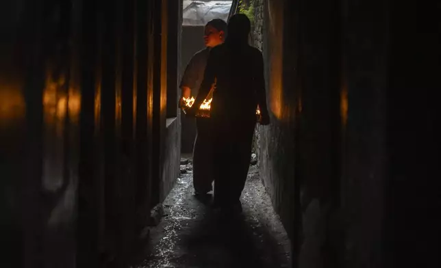 Nepalese vendors carry new butter lamps to sell to devotees during Buddha Jayanti or Buddha Purnima festival in Boudhanath Stupa, Kathmandu, Nepal, Monday, May 12, 2025. (AP Photo/Niranjan Shrestha)