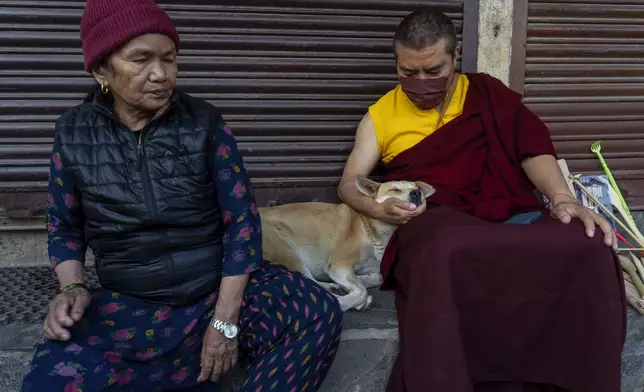 A Buddhist monk pets a stray dog on his lap during Buddha Jayanti, also known as Buddha Purnima festival, to celebrate Buddha's birthday, in Boudhanath Stupa, Kathmandu, Nepal, Monday, May 12, 2025. (AP Photo/Niranjan Shrestha)