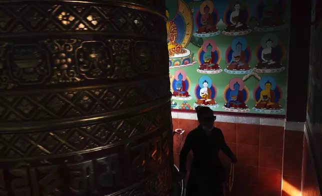 A devotee spins a prayers wheel during Buddha Jayanti, also known as Buddha Purnima festival, to celebrate Buddha's birthday, in Boudhanath Stupa, Kathmandu, Nepal, Monday, May 12, 2025. (AP Photo/Niranjan Shrestha)
