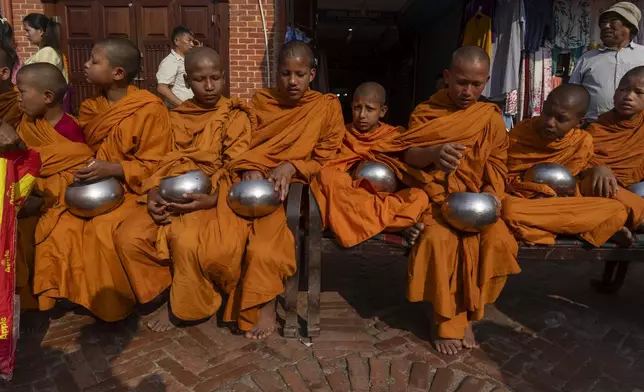Novice Buddhist monks wait for alms during Buddha Jayanti, also known as Buddha Purnima festival, to celebrate Buddha's birthday, in Boudhanath Stupa, Kathmandu, Nepal, Monday, May 12, 2025. (AP Photo/Niranjan Shrestha)