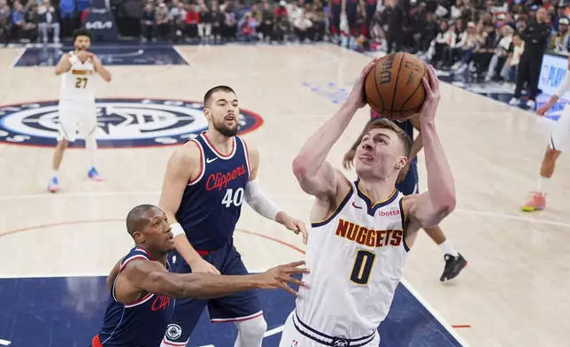 Denver Nuggets guard Christian Braun, right, shoots as Los Angeles Clippers guard Kris Dunn, left, and center Ivica Zubac defend during the first half in Game 6 of an NBA basketball first-round playoff series Thursday, May 1, 2025, in Inglewood, Calif. (AP Photo/Mark J. Terrill)