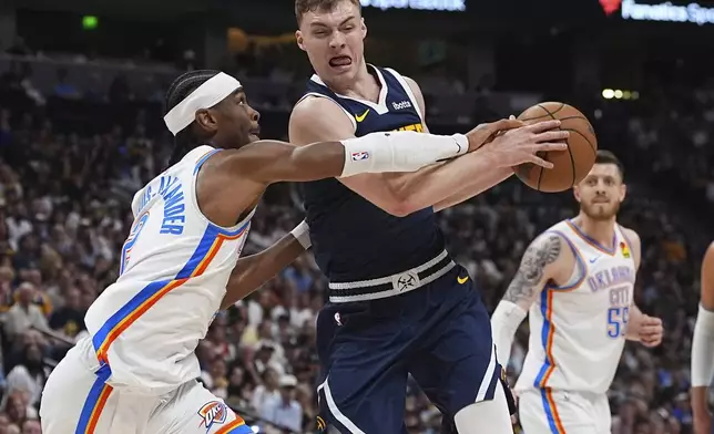 Oklahoma City Thunder guard Shai Gilgeous-Alexander, left, blocks Denver Nuggets guard Christian Braun, front right, on the way to the basket in the first half of Game 4 in the Western Conference semifinals of the NBA basketball playoffs Sunday, May 11, 2025, in Denver. (AP Photo/David Zalubowski)