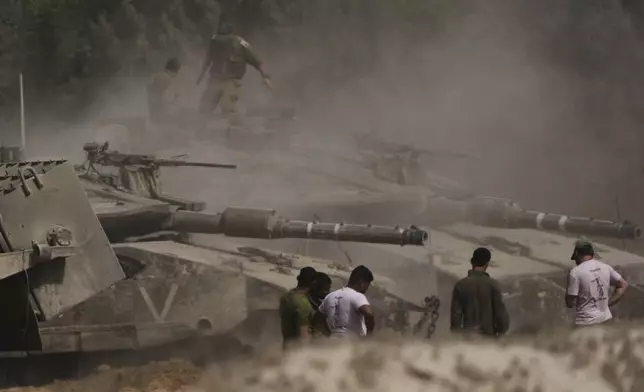 Israeli soldiers work on tanks at a staging area near the border with the Gaza Strip, in southern Israel, Sunday, May 18, 2025. (AP Photo/Ariel Schalit)