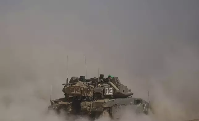 Israeli soldiers move tanks around staging area near the border with the Gaza Strip, in southern Israel, Sunday, May 18, 2025. (AP Photo/Ariel Schalit)