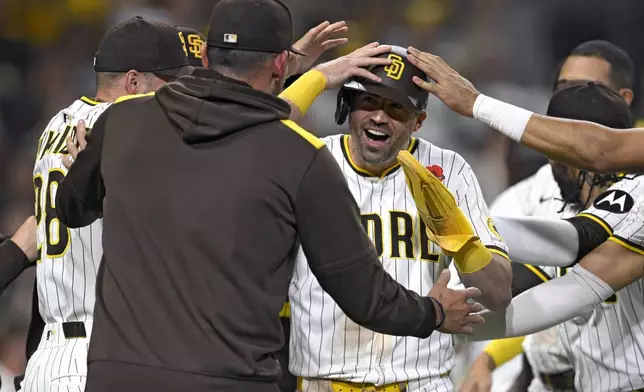 San Diego Padres' Tyler Wade, center, is congratulated after scoring on a wild pitch during the 11th inning of a baseball game to defeat the Miami Marlins, Monday, May 26, 2025, in San Diego. (AP Photo/Orlando Ramirez)