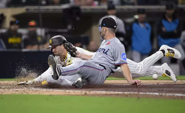 San Diego Padres' Tyler Wade, left, scores on a wild pitch ahead of Miami Marlins relief pitcher Cade Gibson, right, during the 11th inning of a baseball game Monday, May 26, 2025, in San Diego. (AP Photo/Orlando Ramirez)