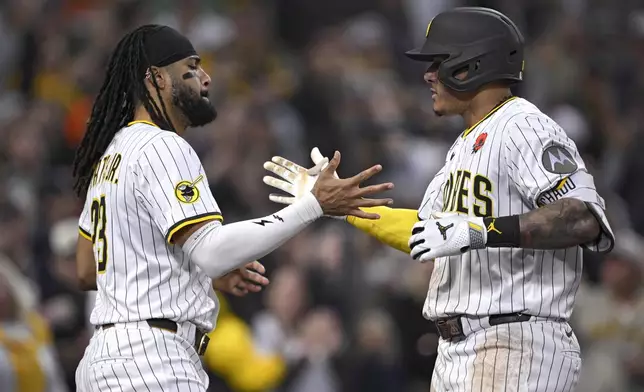 San Diego Padres' Manny Machado, right, celebrates with Fernando Tatis Jr., left, after hitting a home run during the eighth inning of a baseball game against the Miami Marlins, Monday, May 26, 2025, in San Diego. (AP Photo/Orlando Ramirez)