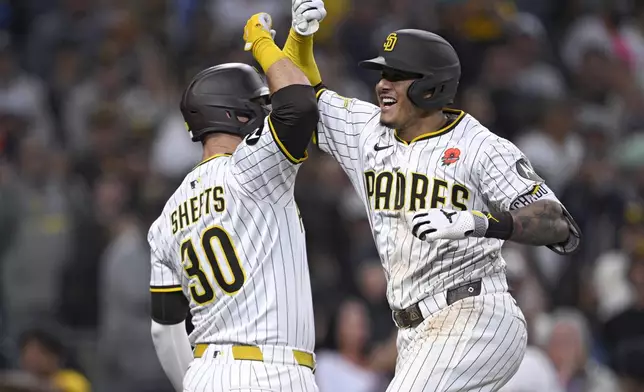 San Diego Padres' Manny Machado, right, celebrates with Gavin Sheets, left, after hitting a home run during the eighth inning of a baseball game against the Miami Marlins, Monday, May 26, 2025, in San Diego. (AP Photo/Orlando Ramirez)