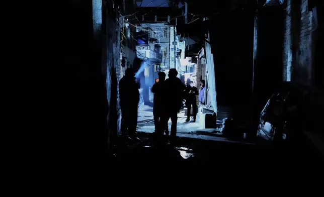Kashmiri boys smoke during a blackout after residents reported hearing explosions and sirens in Srinagar, Indian controlled Kashmir, Friday, May 9, 2025. (AP Photo/Mukhtar Khan)