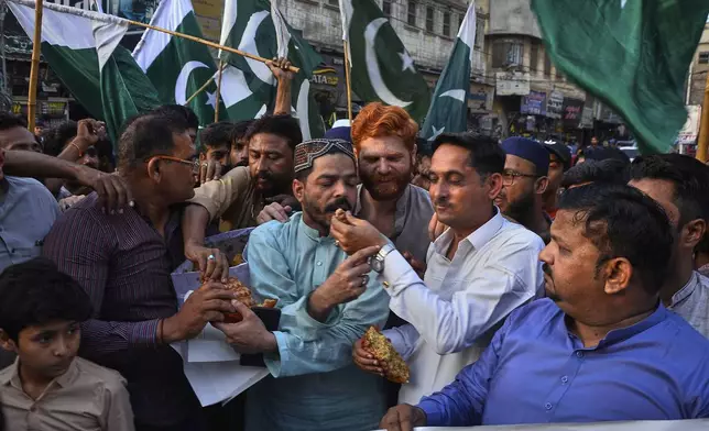 People share cake as they celebrates following India and Pakistan have reached a ceasefire deal, during a demonstration, in Hyderabad, Pakistan, Saturday, May 10, 2025. (AP Photo/Pervez Masih)