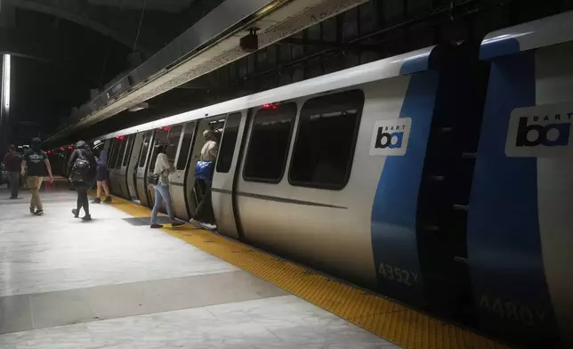 Passengers walk on and off a Bay Area Rapid Transit train at a BART station in San Francisco, Friday, May 9, 2025. (AP Photo/Jeff Chiu)