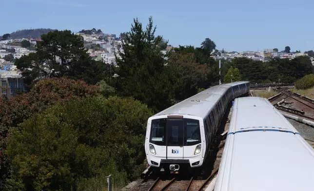 A Bay Area Rapid Transit train, left, approaches a BART station as another departs in Daly City, Calif., Friday, May 9, 2025. (AP Photo/Jeff Chiu)
