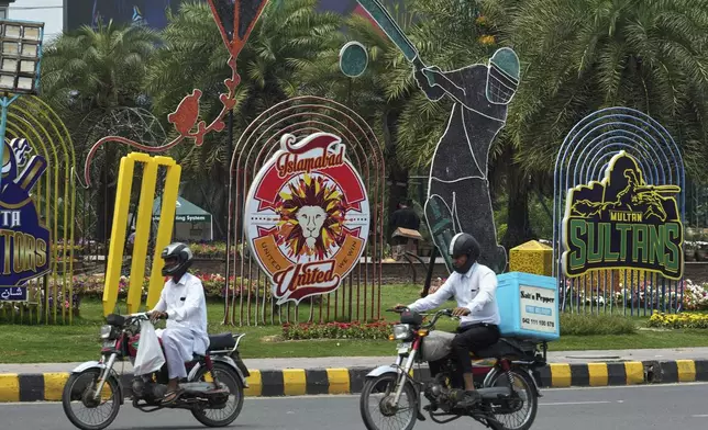 Motorcyclists drive past an advertisement of Pakistan Super League Twenty20 tournament displayed along a roadside in Lahore, Pakistan, Friday, May 9, 2025. (AP Photo/K.M. Chaudary)