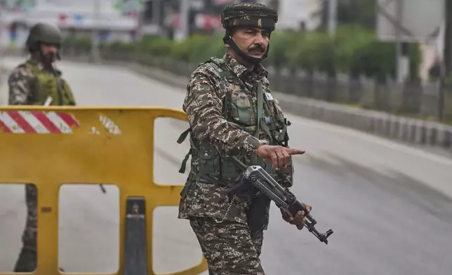 A paramilitary soldier signals to a Kashmiri man to stop at a temporary checkpoint on the road leading to airport after loud explosions were heard in Srinagar, in Indian controlled Kashmir, Saturday, May 10, 2025.(AP Photo/Dar Yasin)