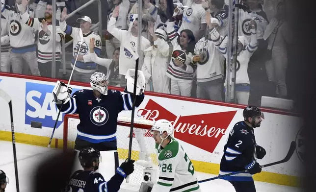 Winnipeg Jets goaltender Connor Hellebuyck (37) celebrates after an empty-net goal by Nikolaj Ehlers on the Dallas Stars during the third period of an NHL hockey playoff game in Winnipeg, Manitoba, Friday, May 9, 2025. (Fred Greenslade/The Canadian Press via AP)