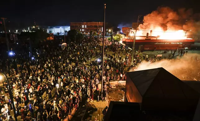 FILE - Protestors demonstrate outside of the burning Minneapolis 3rd Police Precinct in Minneapolis on May 28, 2020. (AP Photo/John Minchillo, File)