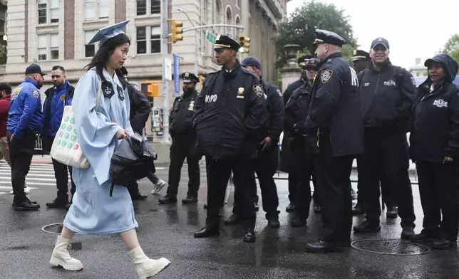 A graduate walks past a police line across the street from the main gates of Columbia University, Wednesday, May 21, 2025, in New York. (AP Photo/Heather Khalifa)