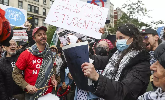Alumni and students burn a diploma across the street from the main gates of Columbia University, Wednesday, May 21, 2025, in New York. (AP Photo/Heather Khalifa)