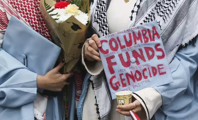 A graduate shows off their decorated cap in support of Palestinians while posing for photos across the street from the main gates of Columbia University, Wednesday, May 21, 2025, in New York. (AP Photo/Heather Khalifa)