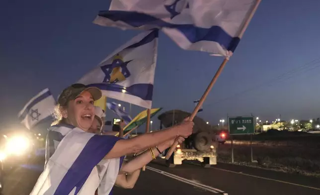 Israelis wave flags as the convoy carrying freed Israeli-American soldier Edan Alexander arrives after his release from Hamas captivity in Gaza to an army base in Reim, near the Gaza border, southern Israel, Monday, May 12, 2025.(AP Photo/Maya Alleruzzo)