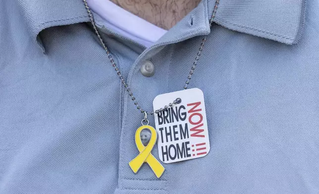 A person wears a necklace in support of hostages held by Hamas as residents and friends gather in Huyler Park ahead of the release of American hostage Edan Alexander from Hamas on Monday, May 12, 2025 in 2025, in Tenafly, N.J. (AP Photo/Stefan Jeremiah)