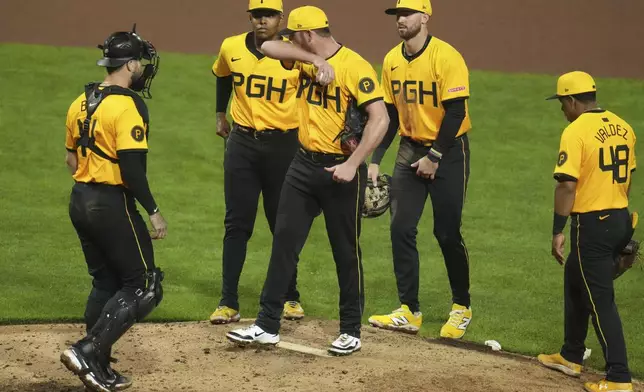 Pittsburgh Pirates pitcher Caleb Ferguson, center, waits with teammates for manager manager Derek Shelton to pull him from a baseball game against the San Diego Padres during the eighth inning in Pittsburgh, Friday, May 2, 2025. (AP Photo/Gene J. Puskar)