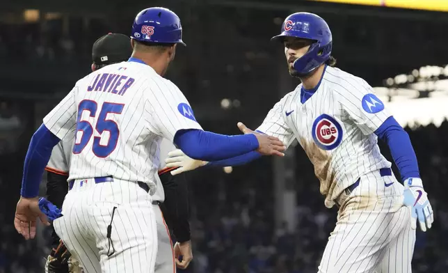 Chicago Cubs' Dansby Swanson, right, celebrates with first base coach Jose Javier (65) after hitting a two-run single during the fourth inning of a baseball game against the San Francisco Giants in Chicago, Monday, May 5, 2025. (AP Photo/Nam Y. Huh)