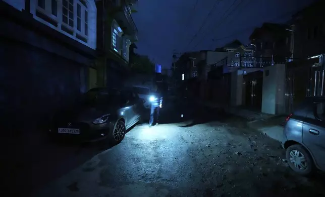 A Kashmiri man using mobile light during blackout is seen after residents of the city of Jammu reported hearing explosions and sirens in Srinagar, Indian controlled Kashmir, Thursday, May 8, 2025. (AP Photo/Mukhtar Khan)