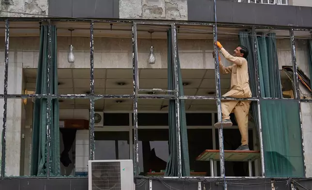 A worker repairs broken glass of a building at the parking area of Rawalpindi Cricket Stadium, where a suspected Indian drone was crashed on Thursday, in Rawalpindi, Pakistan, Friday, May 9, 2025. (AP Photo/Anjum Naveed)