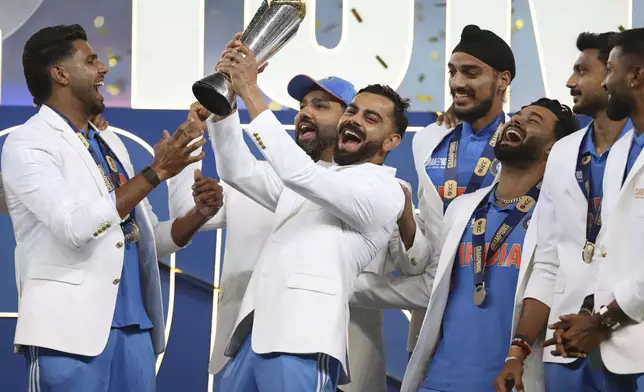 FILE - India's Virat Kohli and teammates celebrate with the winners trophy on the podium after defeating New Zealand in the final cricket match of the ICC Champions Trophy at Dubai International Cricket Stadium in Dubai, United Arab Emirates, on March 9, 2025. (AP Photo/Christopher Pike, File)