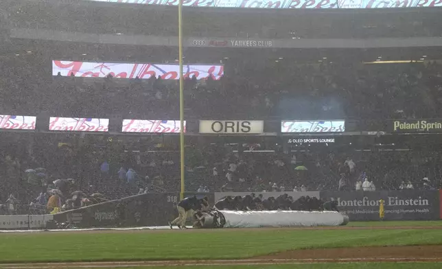 Grounds crew members cover the infield during a rain delay in the during the fourth inning of a baseball game between the New York Yankees and the San Diego Padres, Monday, May 5, 2025, in New York. (AP Photo/Pamela Smith)