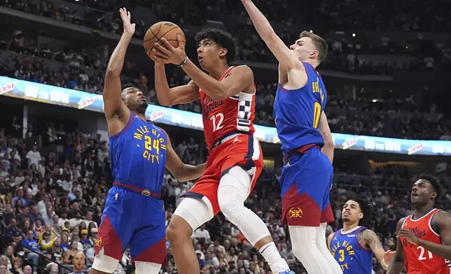 Los Angeles Clippers guard Cam Christie, center, drives to the basket between Denver Nuggets guards Jalen Pickett, left, and Christian Braun in the second half of Game 7 of an NBA basketball first-round playoff series Saturday, May 3, 2025, in Denver. (AP Photo/David Zalubowski)