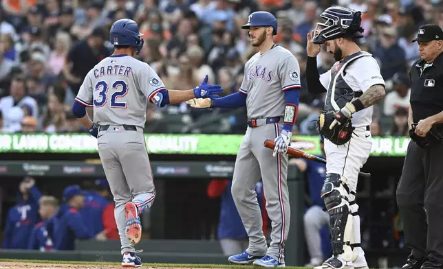 Texas Rangers' Evan Carter (32) celebrates with teammate Jonah Heim, second from left, after hitting a home run in the second inning of a baseball game against the Detroit Tigers, Saturday, May 10, 2025, in Detroit. (AP Photo/Lon Horwedel)