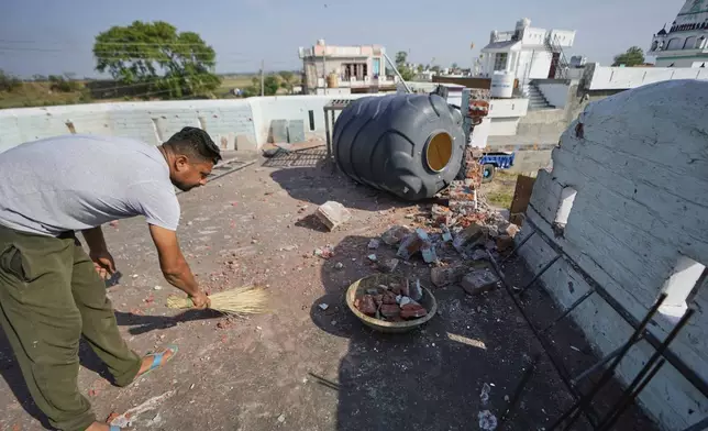A villager cleans the roof of his house damaged by Pakistani artillery shelling at RS Pura, along the International Border, India, Monday, May 12, 2025, after the two countries reported no incidents of firing overnight. (AP Photo/Channi Anand)