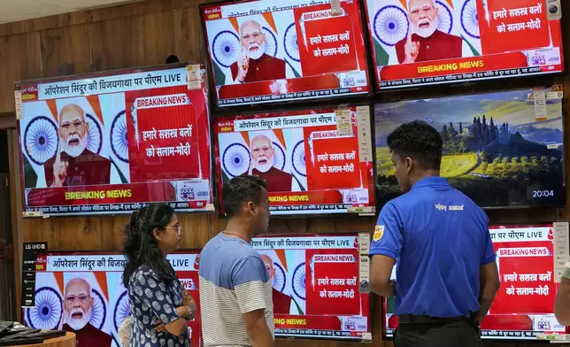 People watch the live telecast of Indian Prime Minister Narendra Modi's speech on television screens at a shopping mall after 'Operation Sindoor' in Mumbai, India, Monday, May 12, 2025. (AP Photo/Rajanish Kakade)